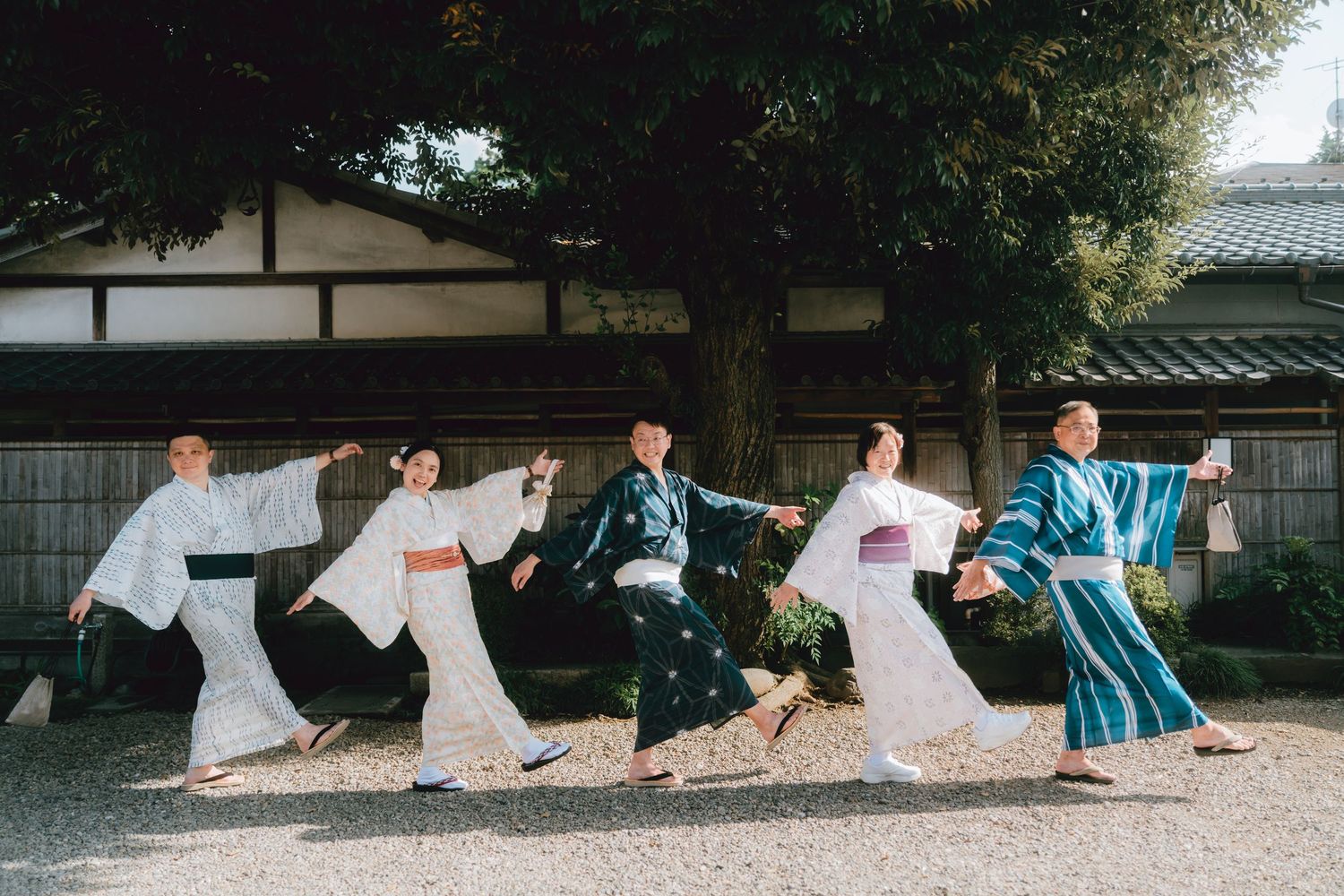 Five people in traditional Japanese kimonos pose mid-jump in unison outside a historic Japanese building in Kawagoe, Japan.