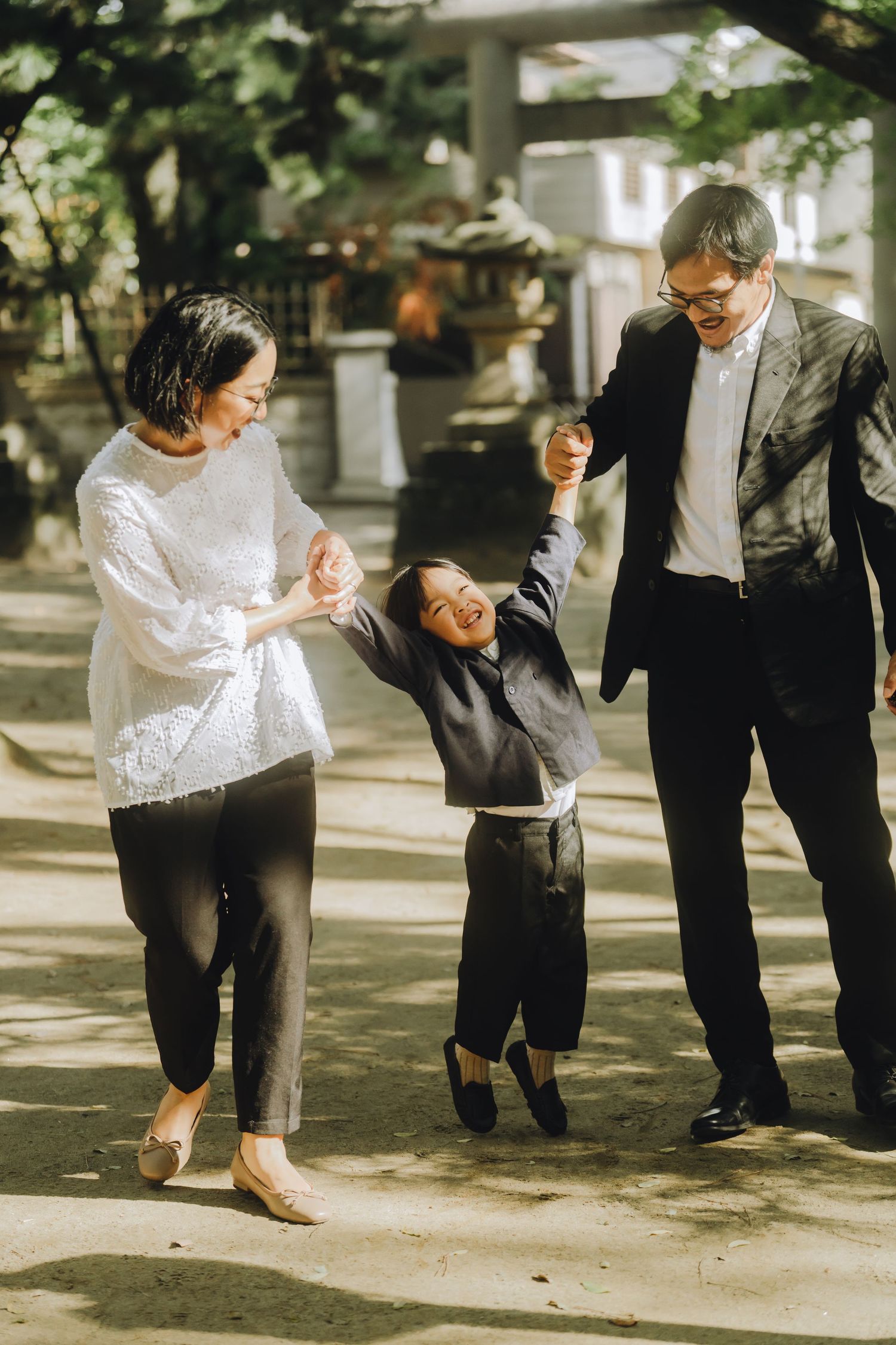 Family of three enjoying a playful moment outdoors, parents swinging their laughing child between them.