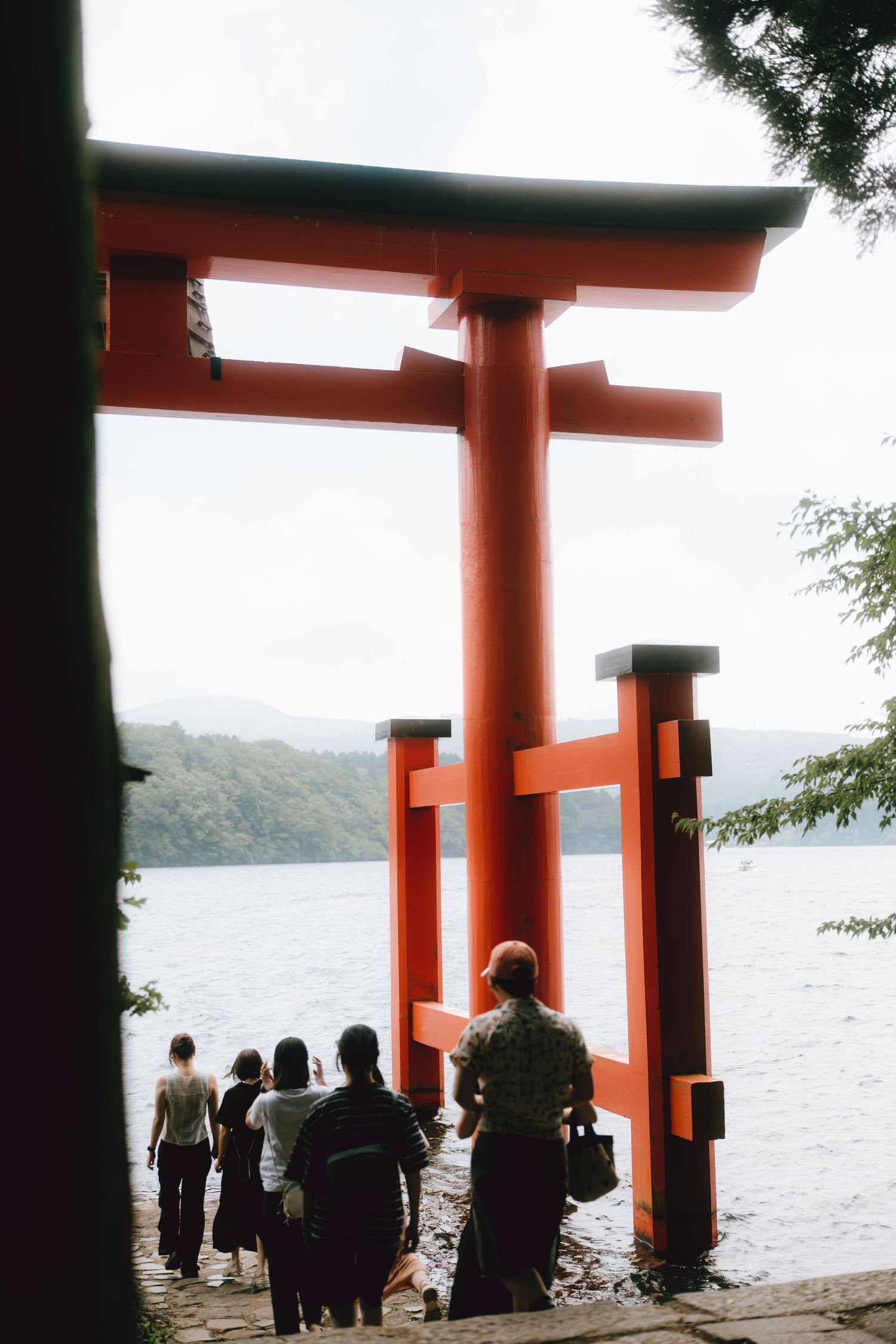 Visitors standing before a red torii gate at hakone shrine in Japan.