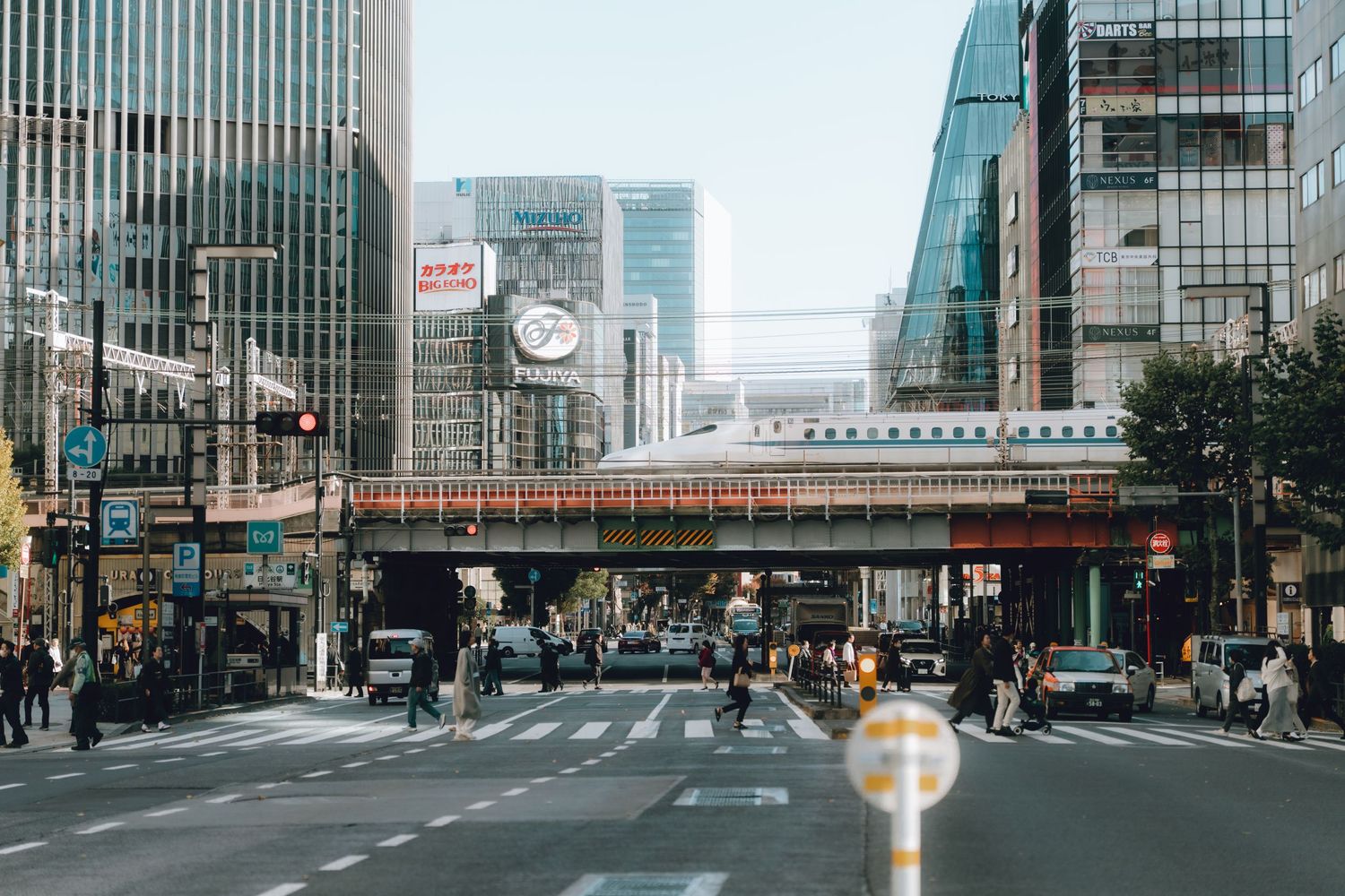 Busy urban intersection with pedestrians and elevated train in Tokyo, Japan.