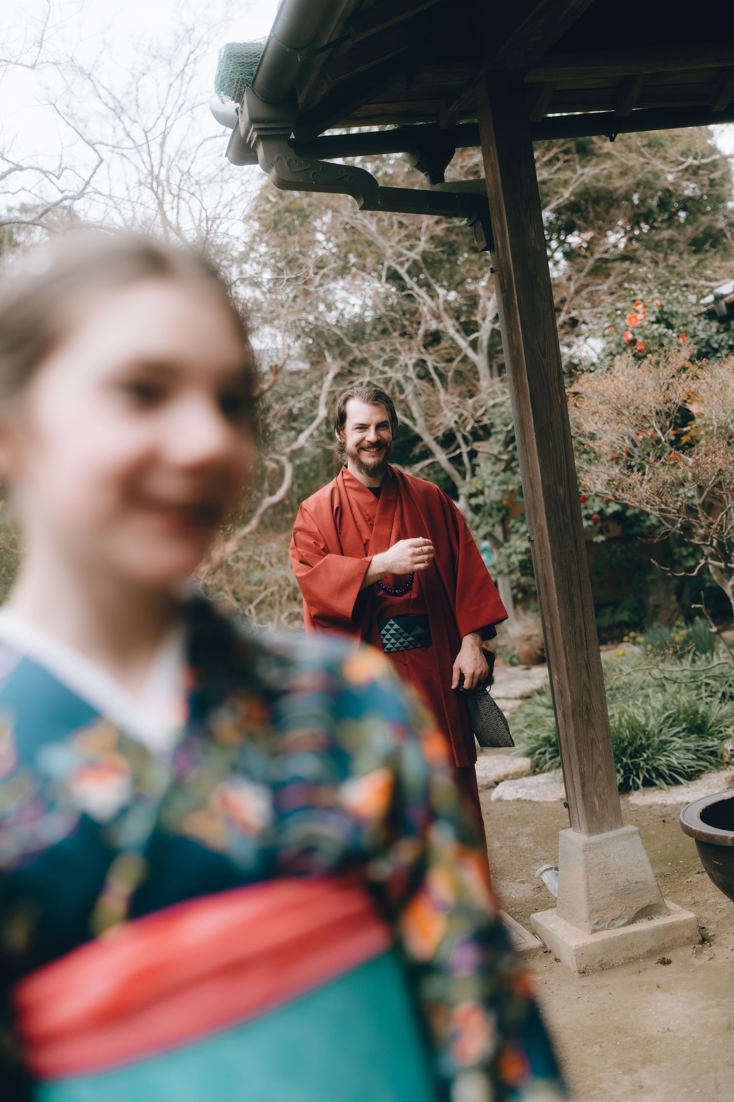 Couple wearing traditional Japanese kimono outfits in a serene garden setting, smiling at each other.Sawara, Chiba, Japan.
