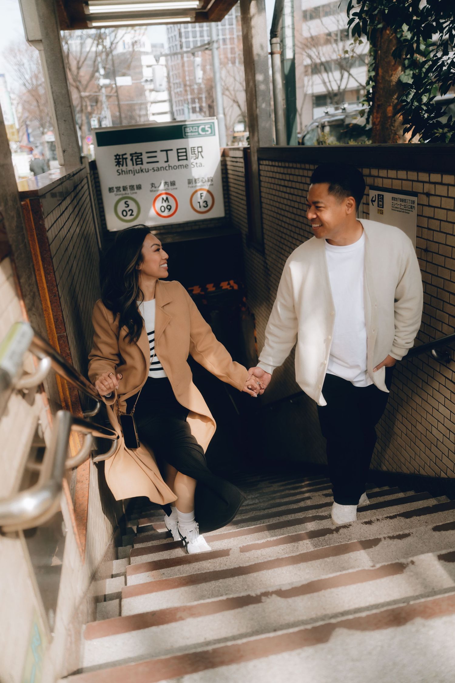 Couple holding hands on stairs at Shinjuku-sanchome Station in shinjyuku, Tokyo.