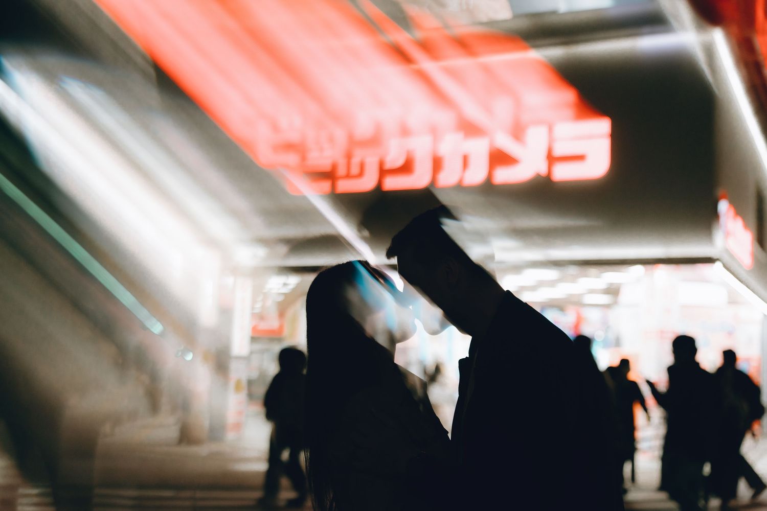 Silhouette of a person against glowing red Japanese neon signs in a bustling urban night scene.