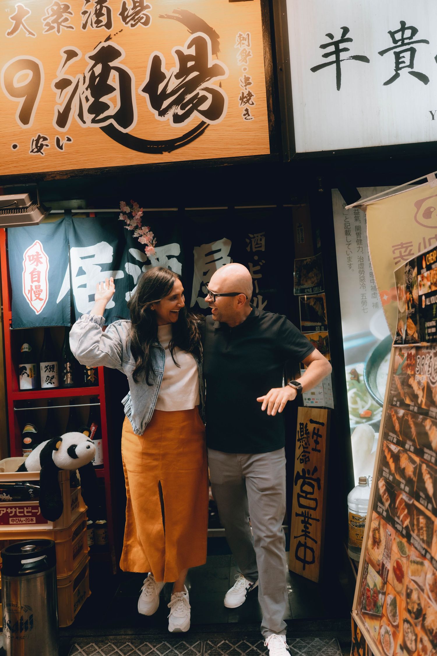 Couple smiling together outside a traditional Japanese izakaya restaurant with kanji signage in ueno, Japan.