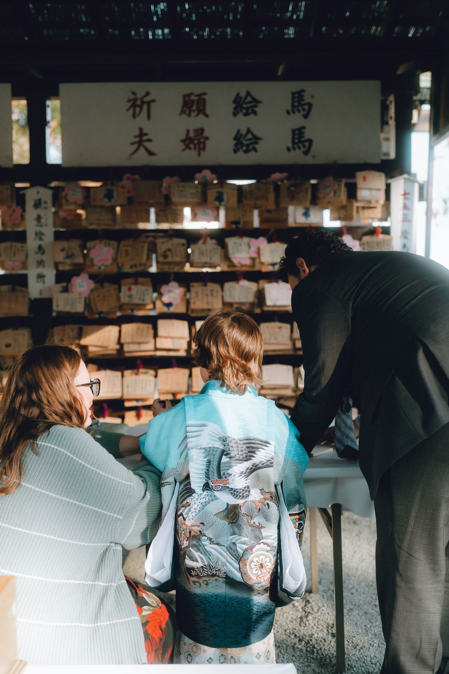 Family viewing ema wooden wishing plaques at a Japanese Shinto shrine in