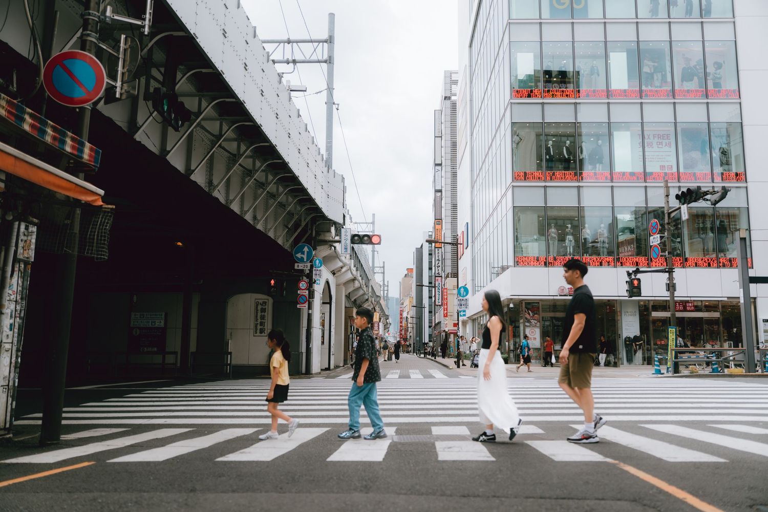People crossing a zebra crossing on a busy urban street in Japan with modern buildings and city infrastructure in Ueno, Tokyo.