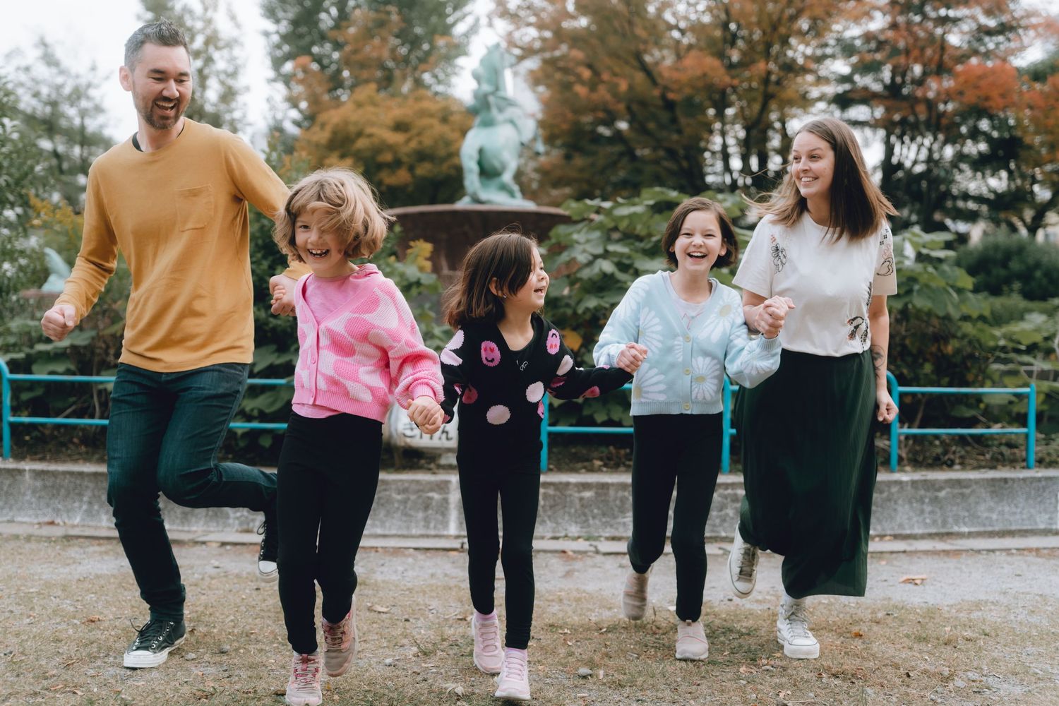 Happy family with three children laughing and running together in an autumn park in tokyo, Japan.