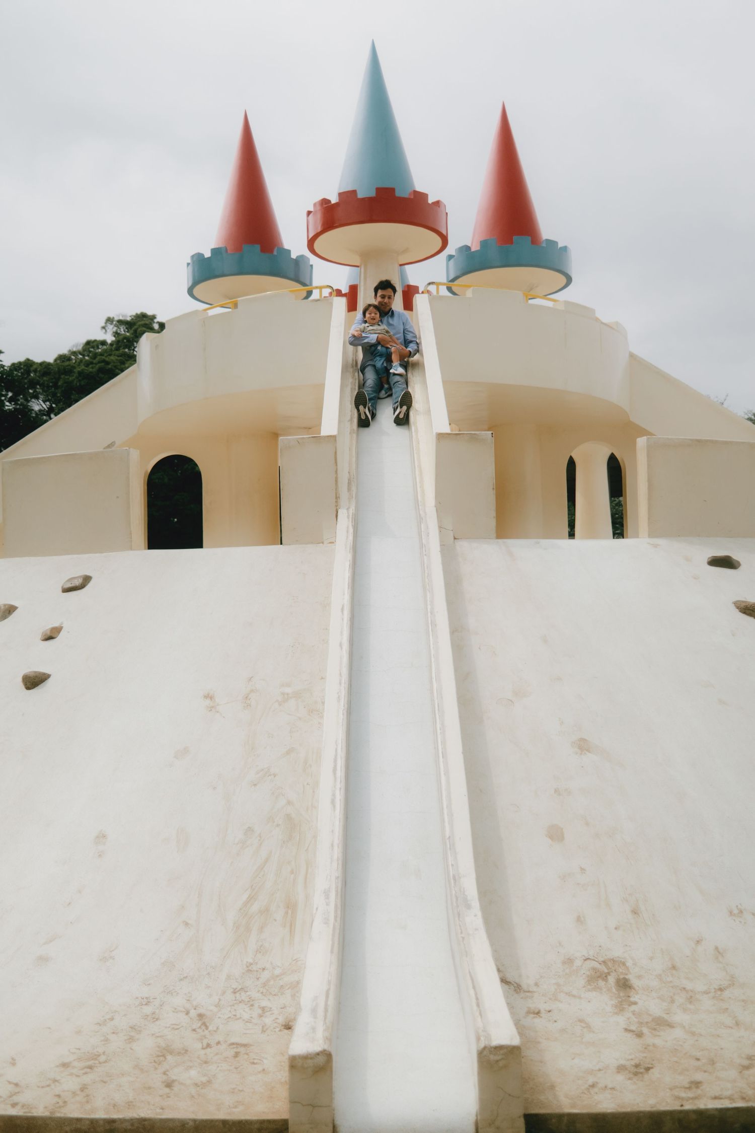 A child sliding down a white castle-themed playground slide at Asukayama Park in Tokyo, Japan.
