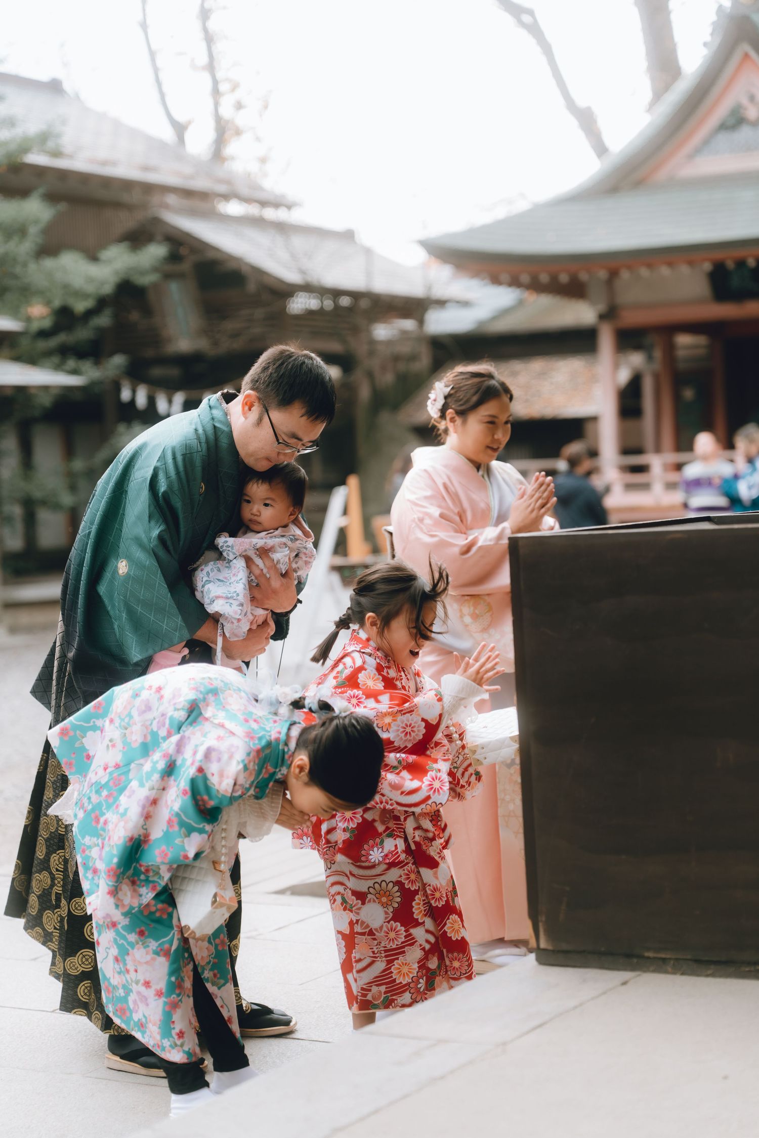Japanese family in traditional kimono praying at a Shinto shrine during a ceremonial celebration.