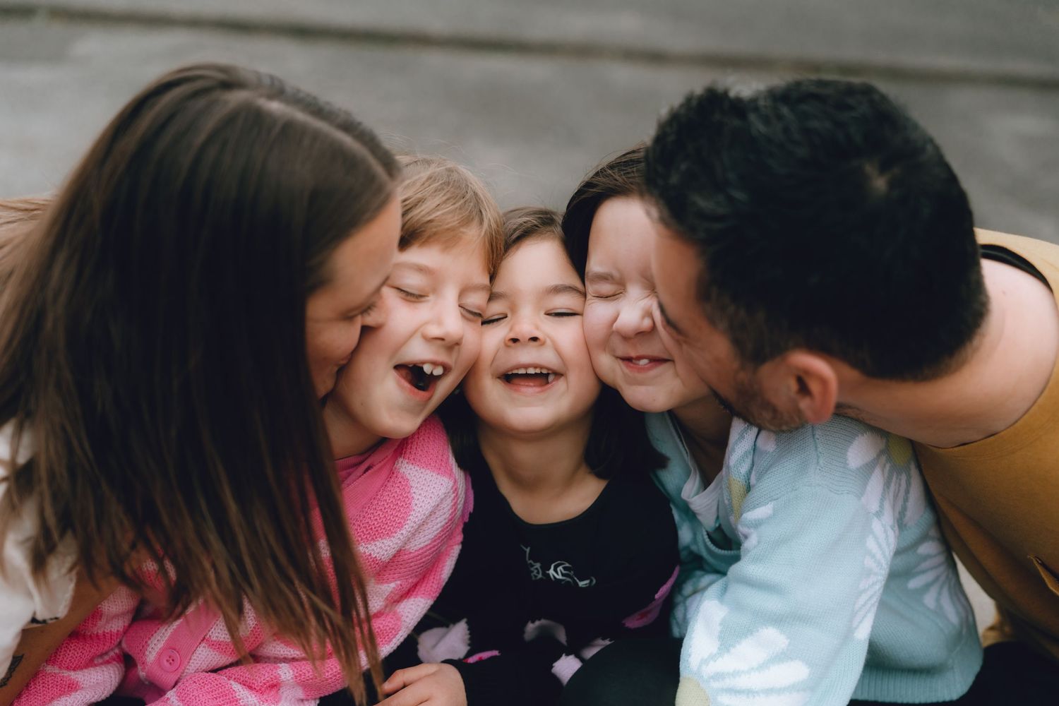 Father and three children sharing a joyful group hug and laughter outdoors in tokyo.