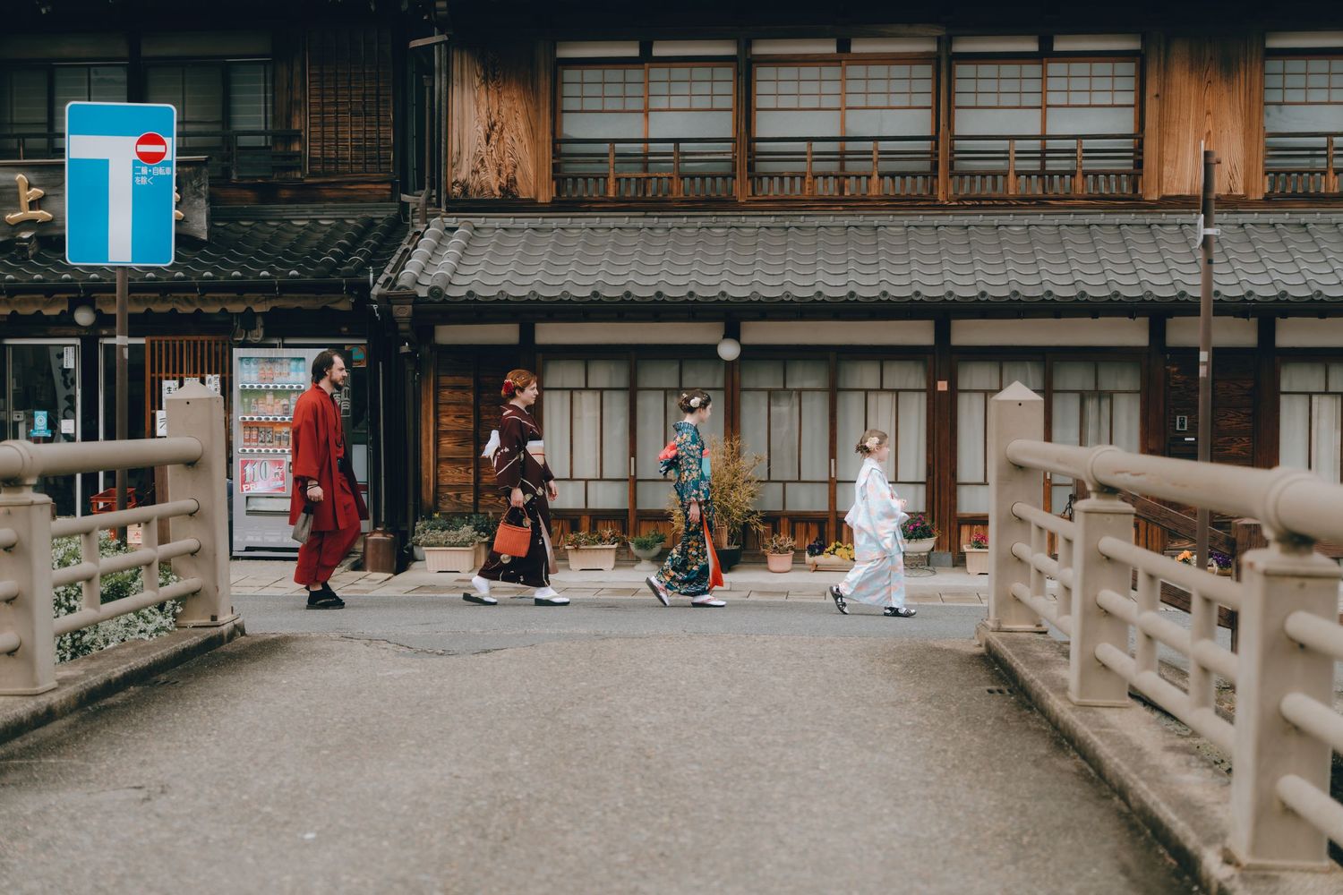 People in traditional Japanese kimono walk past a historic wooden building on a quiet street in Sawara, Chiba, Japan.