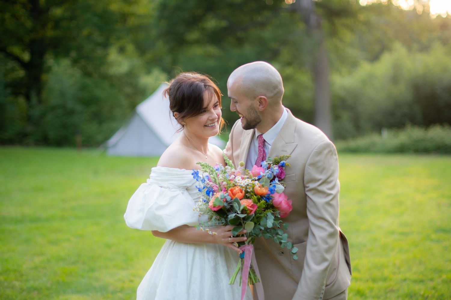 Portrait photo of the wedding couple looking at each other smiling, it is sharp with high contrast and a blurry background.