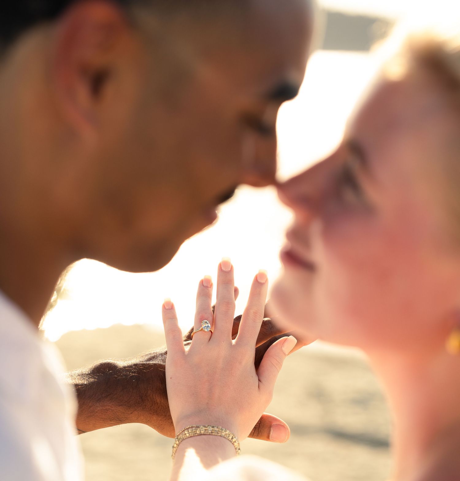 Romantic couple sharing a tender moment, woman displaying diamond engagement ring and gold bracelet.