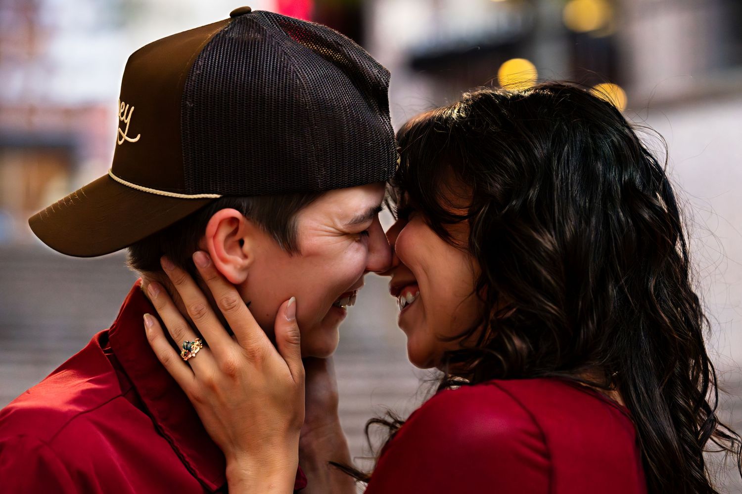 Couple in red outfits sharing a joyful, intimate moment outdoors at night, smiling and touching foreheads.