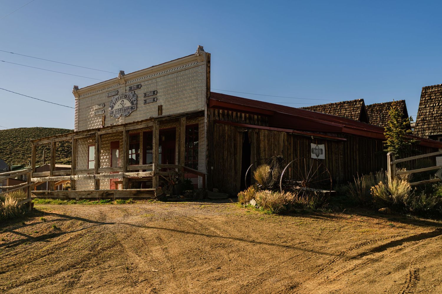 Abandoned old west ghost town building with weathered wood facade on a dirt road under clear blue sky.