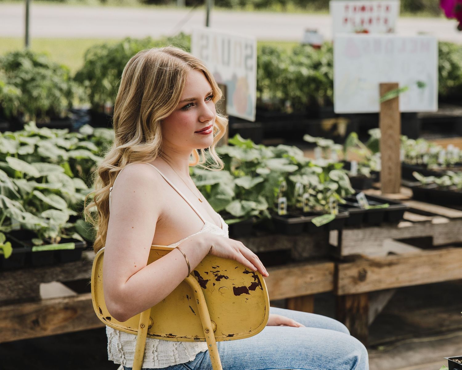 Young blonde woman holding yellow purse at outdoor farmers market.