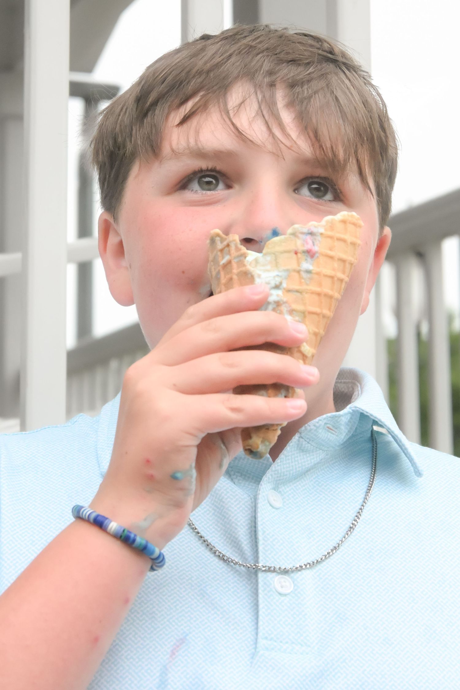 Young boy enjoys a melting ice cream cone on a warm summer day.
