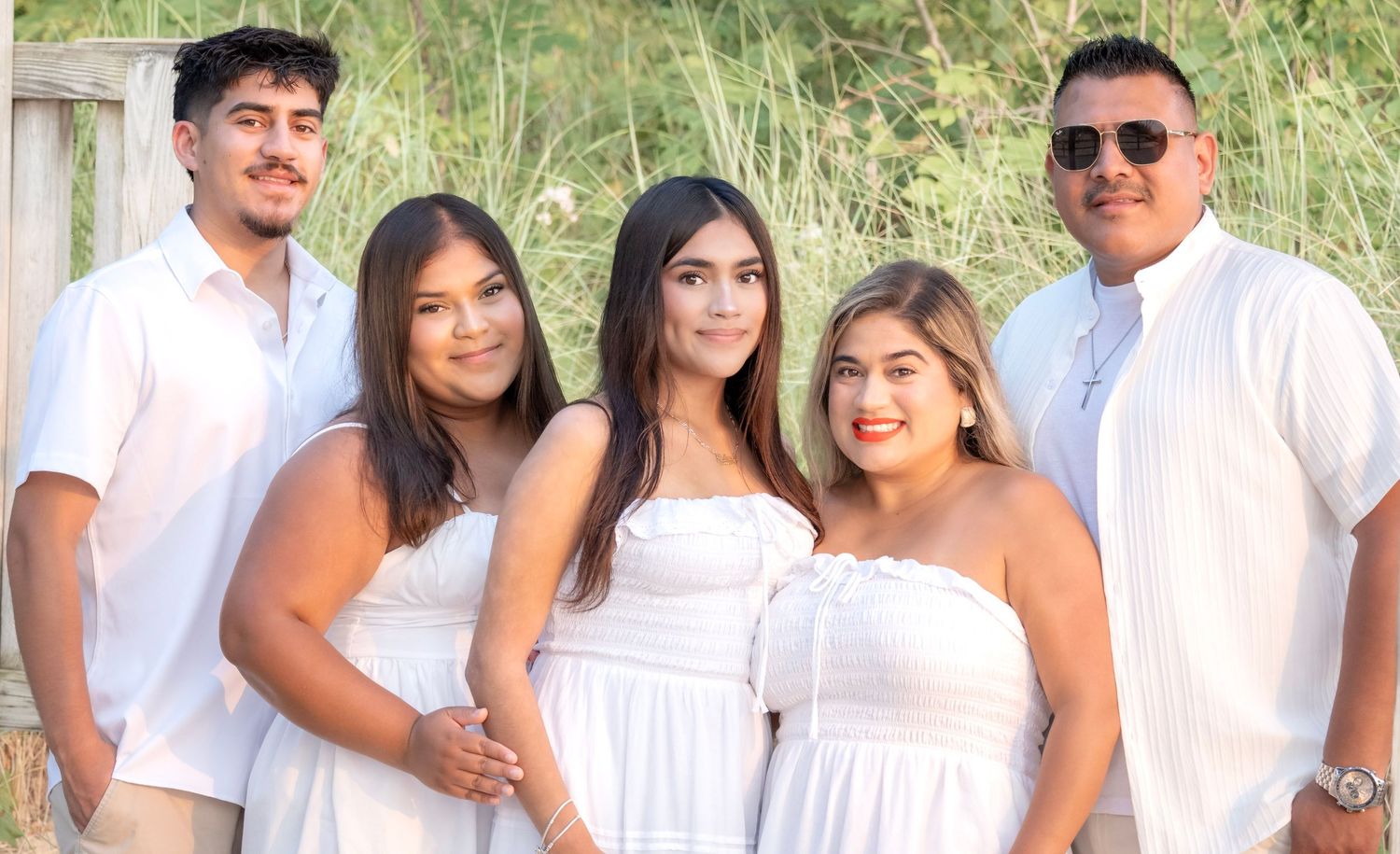 Five people in matching white outfits pose together outdoors for a family portrait photo.