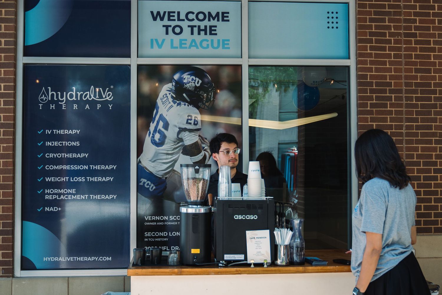Hydralive Therapy IV league wellness clinic interior with staff member at reception desk and menu board displaying services.