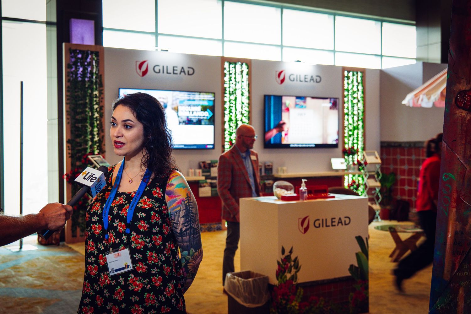 Woman being interviewed at a Gilead Sciences pharmaceutical booth during a professional conference event.
