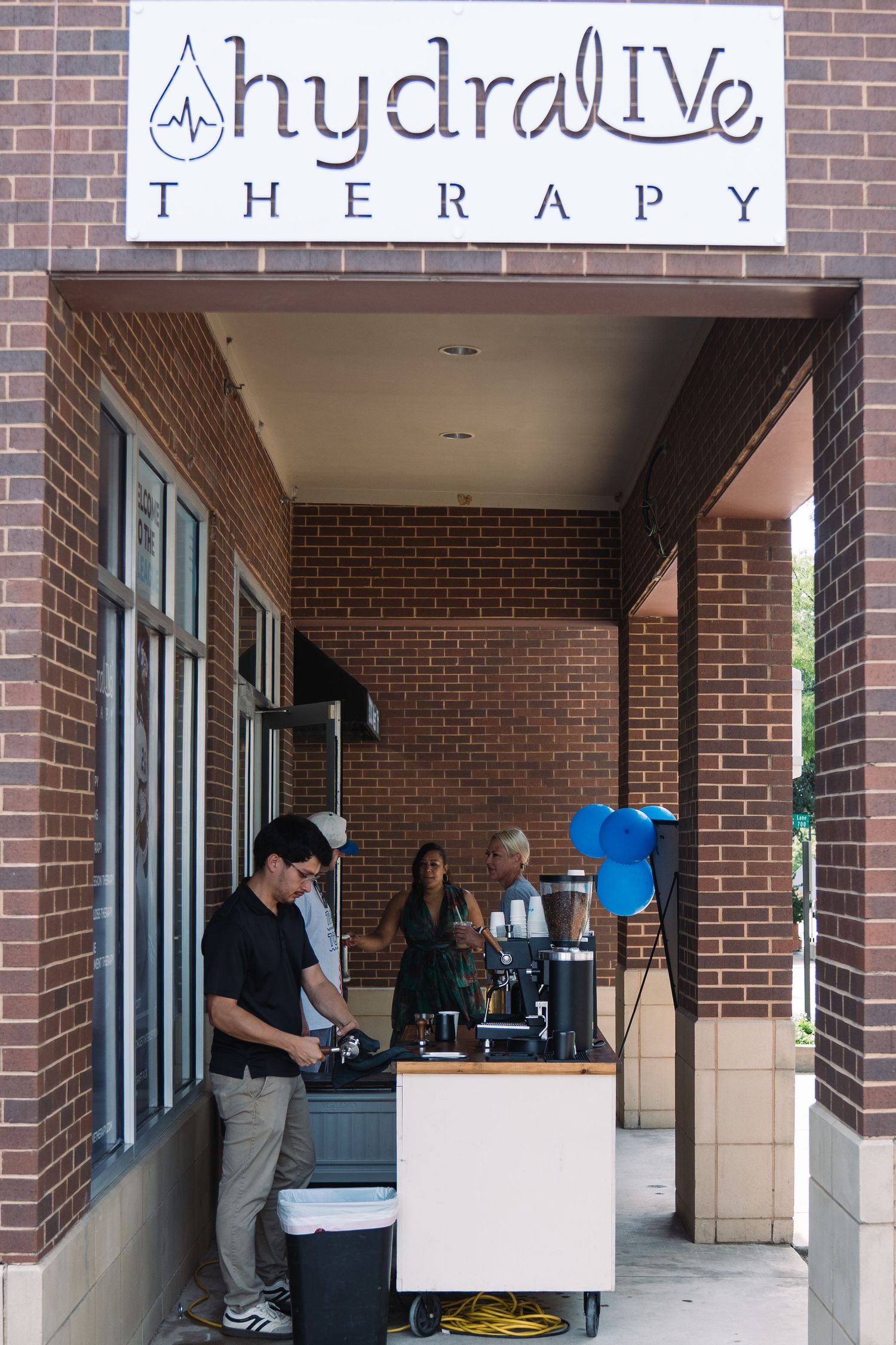 HydraLive Therapy clinic entrance with staff preparing equipment outside a brick building.