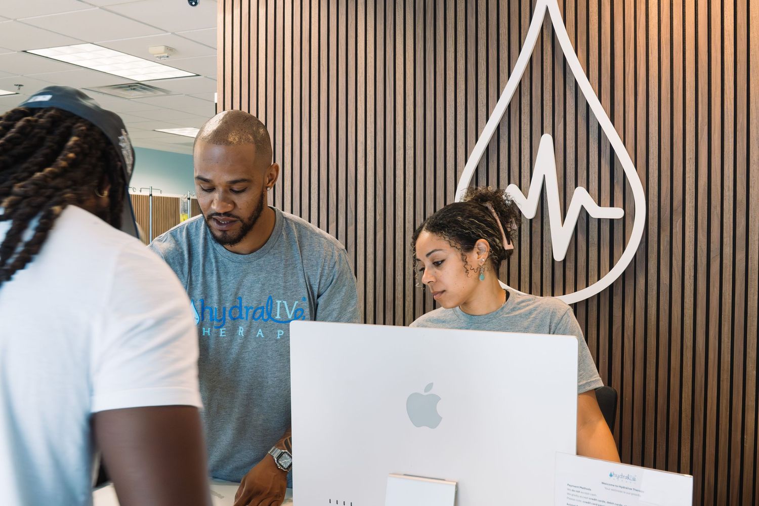 Healthcare staff members collaborating at a modern hydration clinic reception desk with logo.