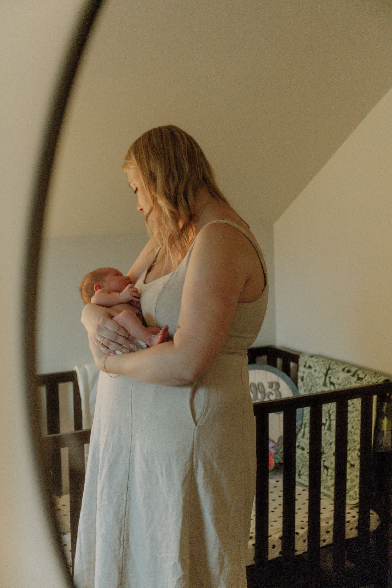 Kawartha Lakes Newborn Photography Session.
Mom holding newborn baby girl looking at her through the nursery mirror