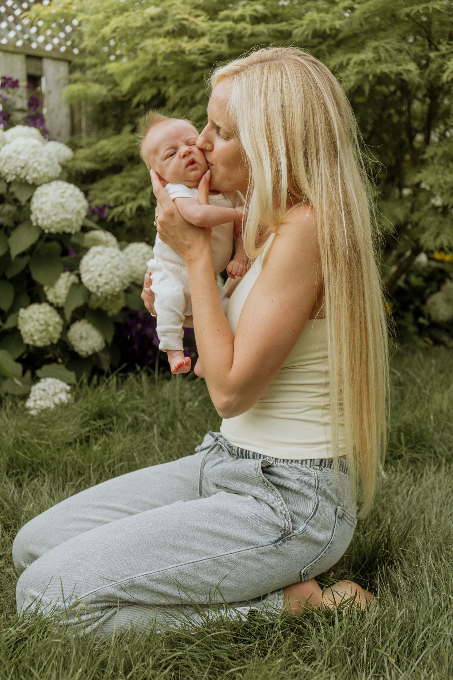 Kawartha Lakes Newborn Photography Session.
Mom holding newborn baby girl in backyard garden kissing her cheek