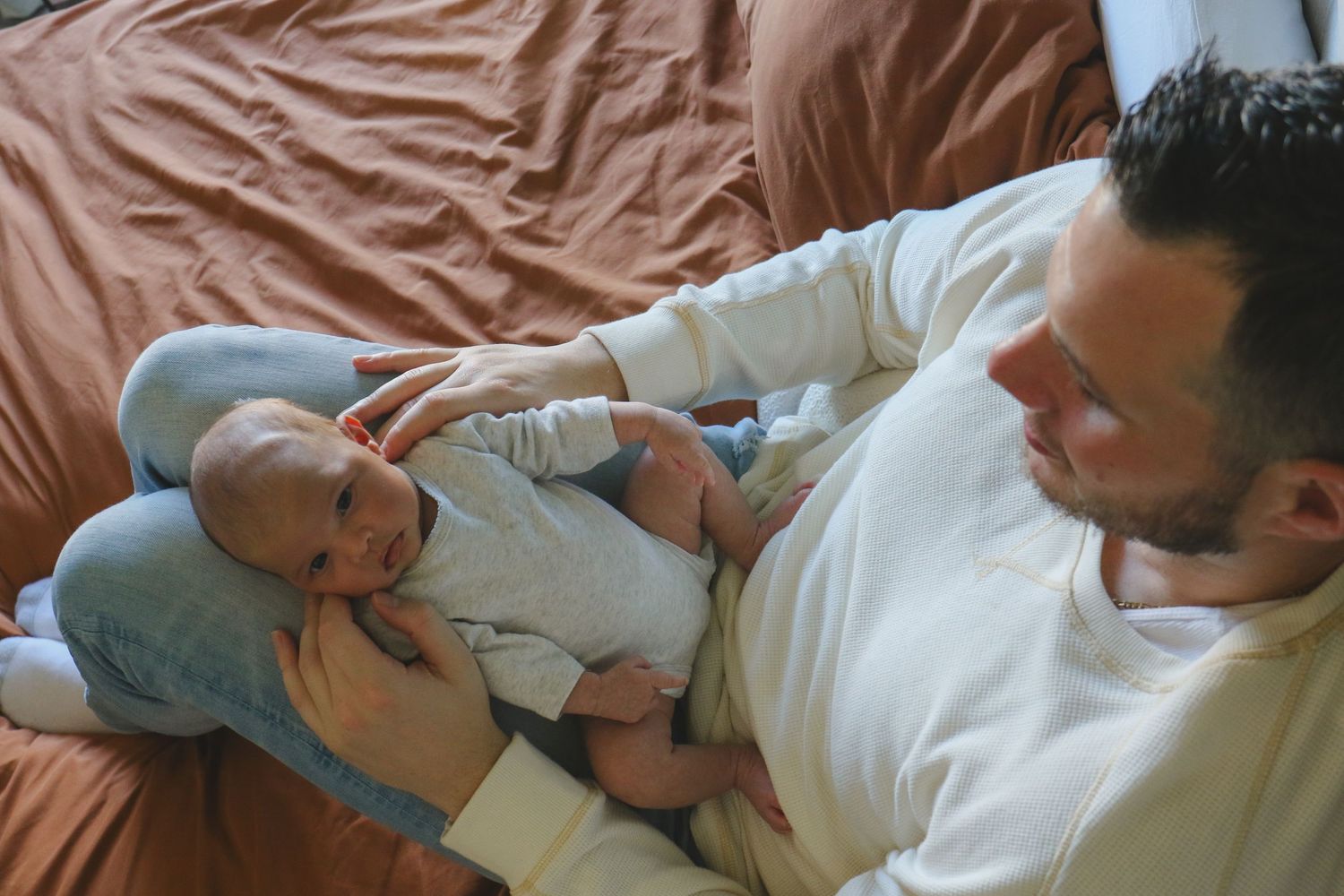 Kawartha Lakes Newborn Photography Session.
Dad holding baby girl newborn daughter on his legs looking at eachother
