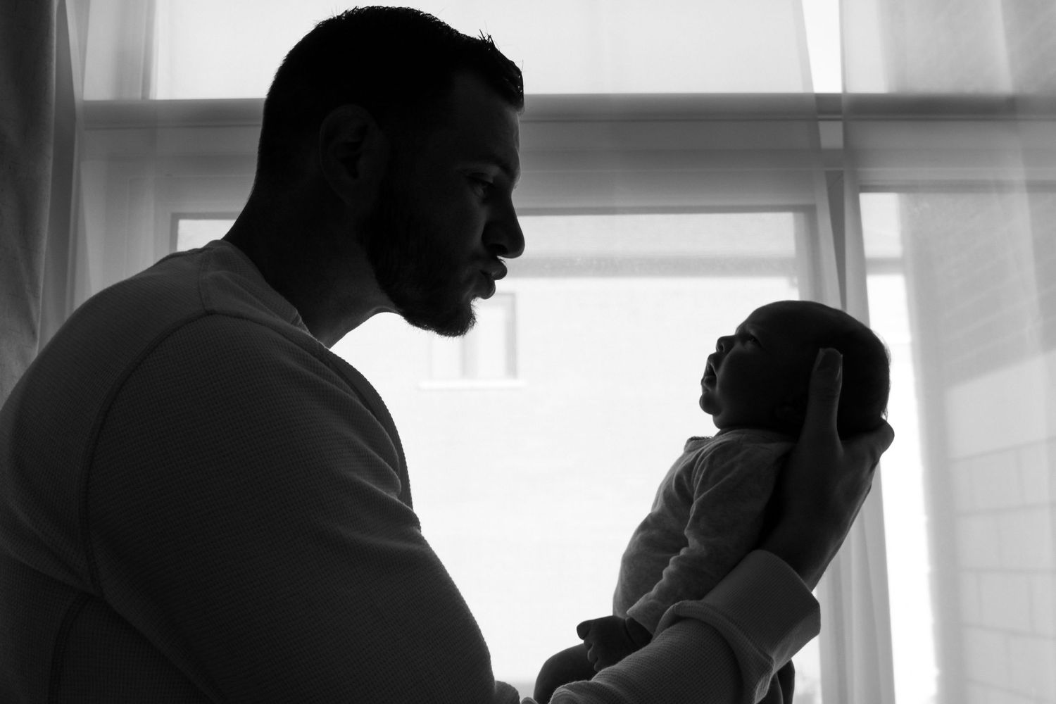 Kawartha Lakes Newborn Photography Session.
Black and white photo of dad holding baby girl newborn daughter. Silhouette