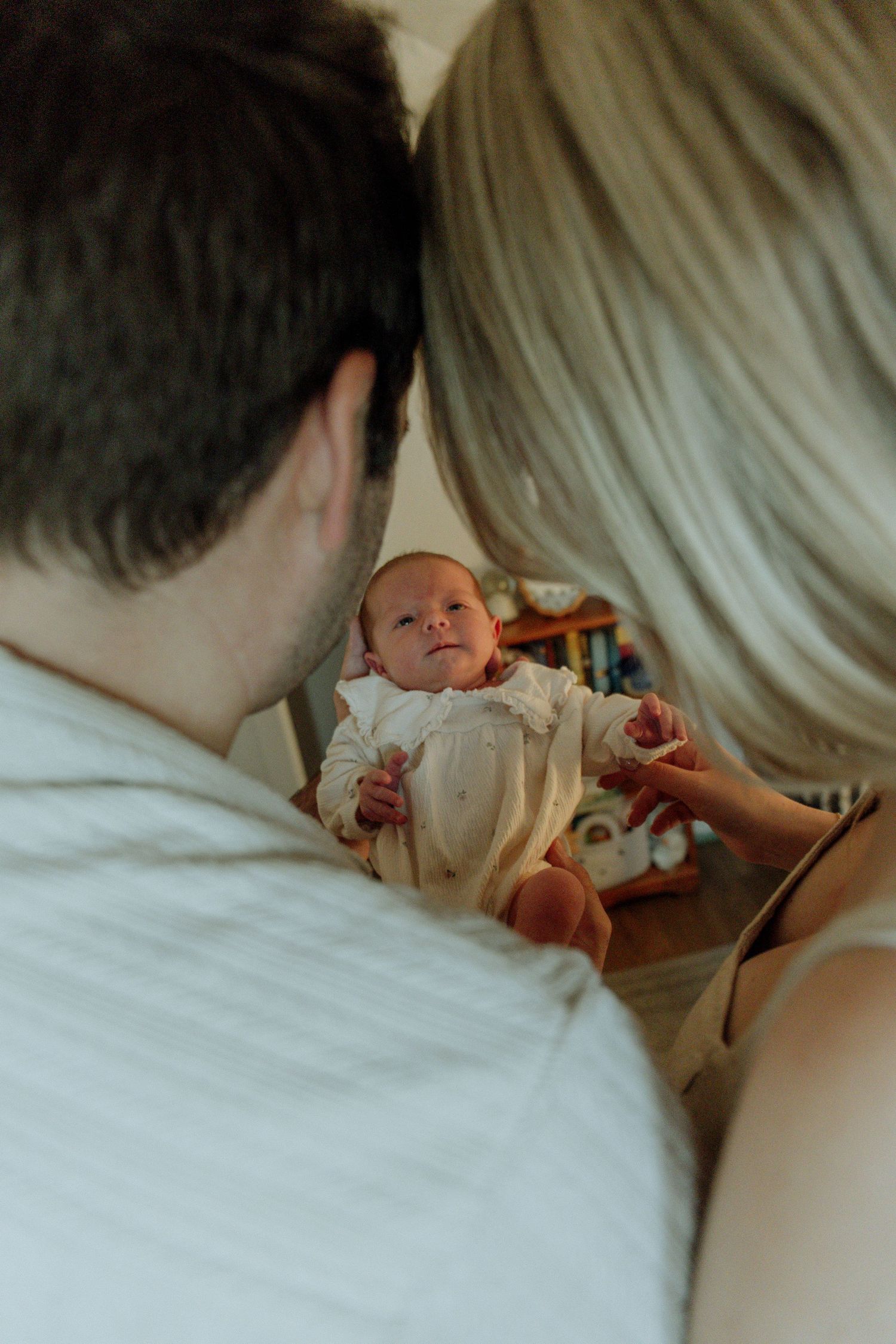 Kawartha Lakes Newborn Photography Session.
Mom and dad with newborn baby girl between them looking at her and shes smiling back