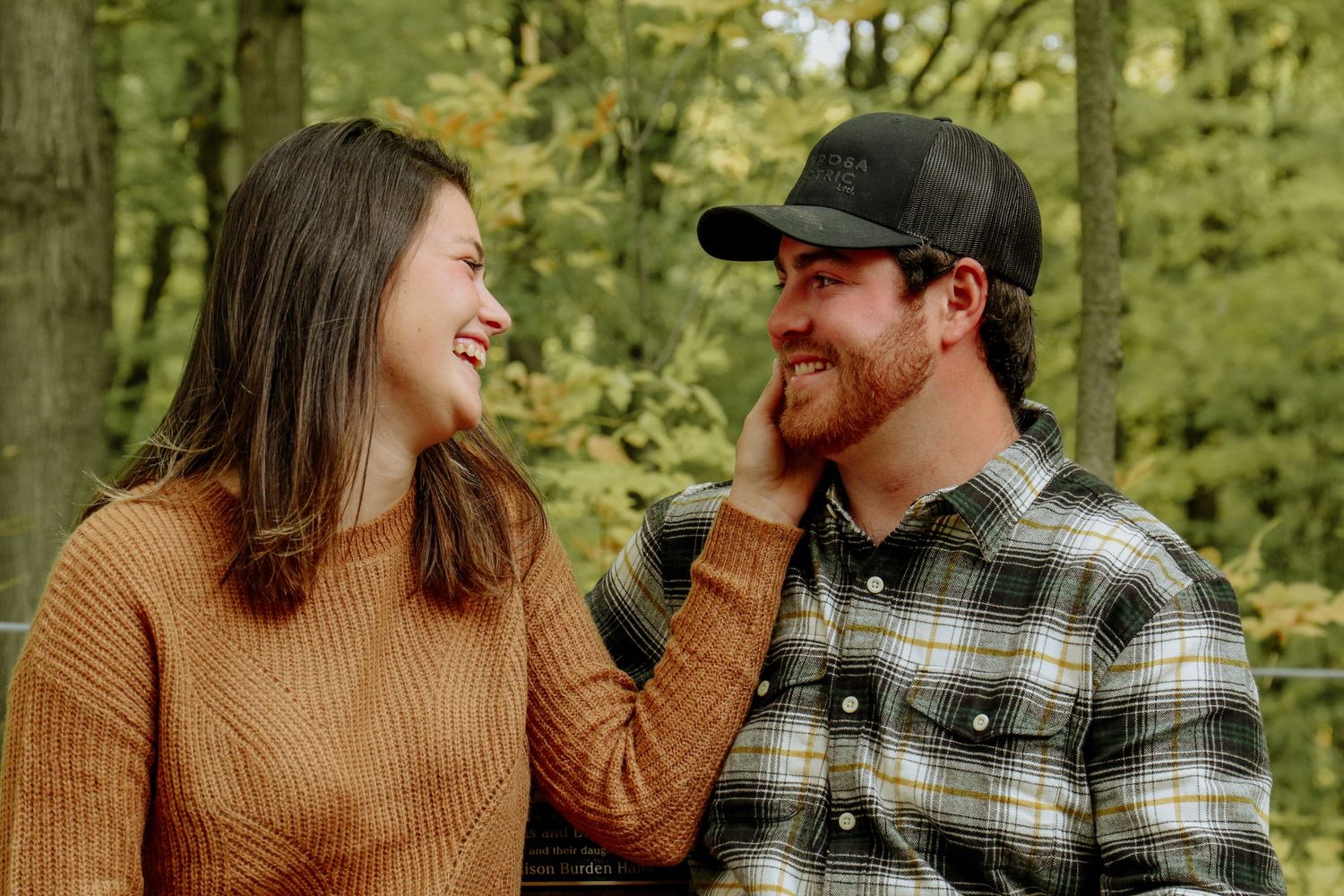 Kawartha Lakes Couple Photography Session.
Boyfriend and girlfriend sitting on a bench together smiling. Girlfriend holding boyfriends face