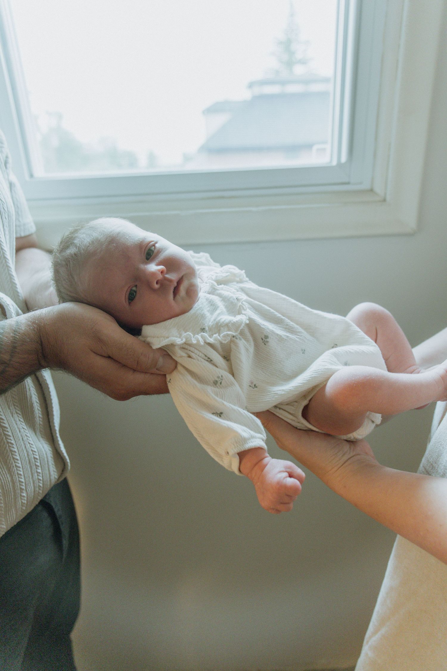 Kawartha Lakes Newborn Photography Session.
Mom and dad holding newborn baby girl between them. Daughter looking at camera