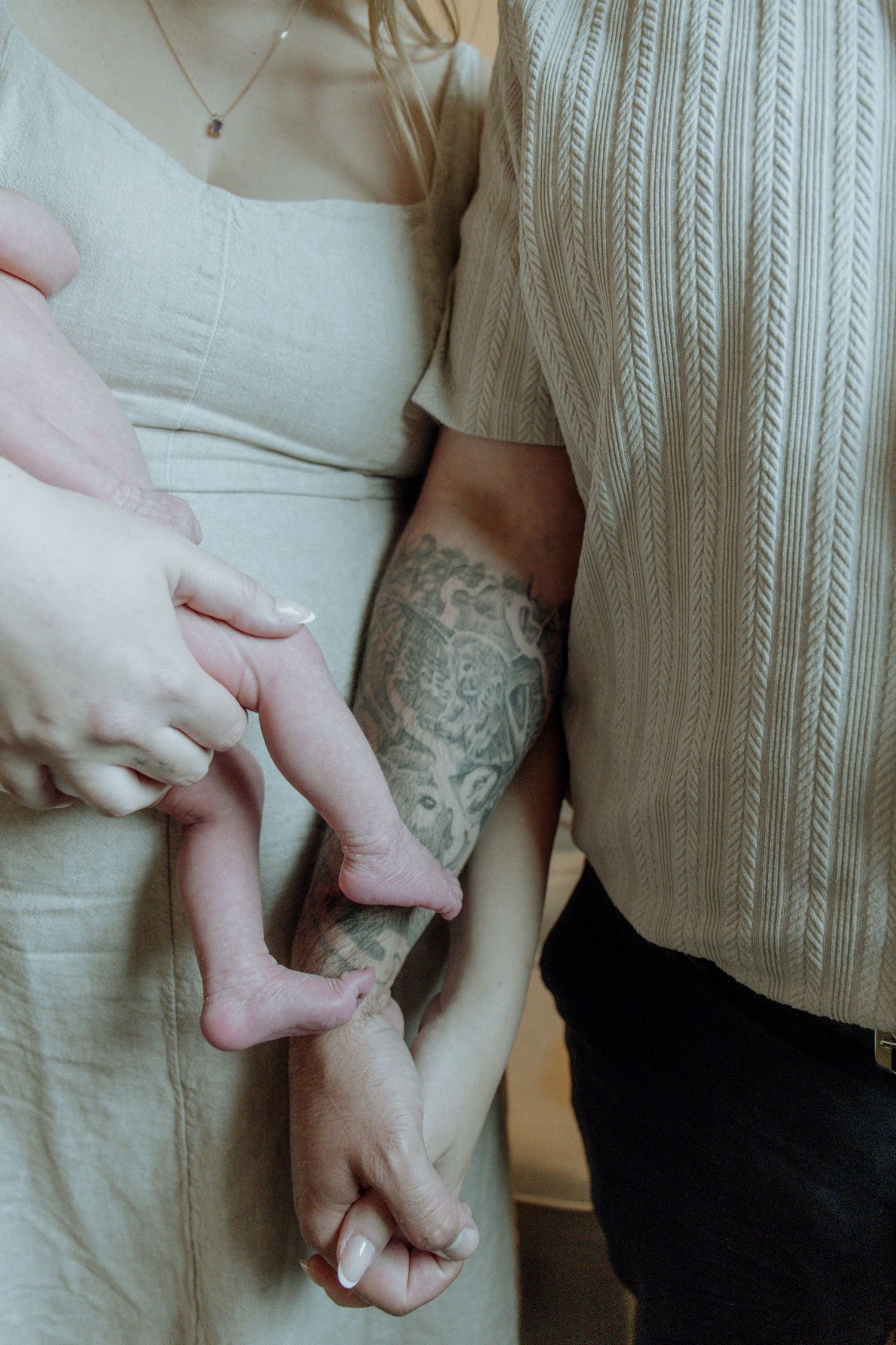 Kawartha Lakes Newborn Photography Session.
Close up detail photo of mom and dad holding hands while mom is holding newborn baby girl feet
