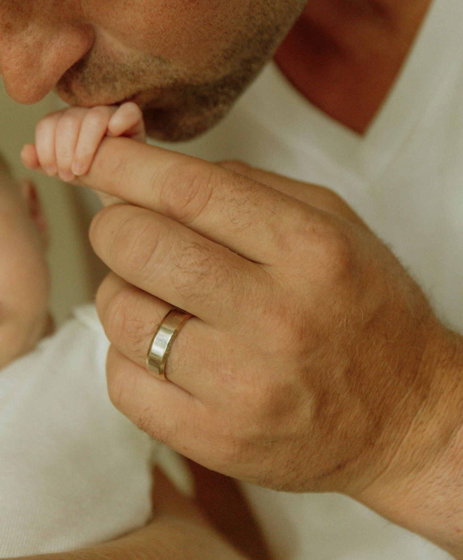 Kawartha Lakes Newborn Photography Session.
Close up detail photo of dad kissing newborn baby girls hand while wrapped around his finger