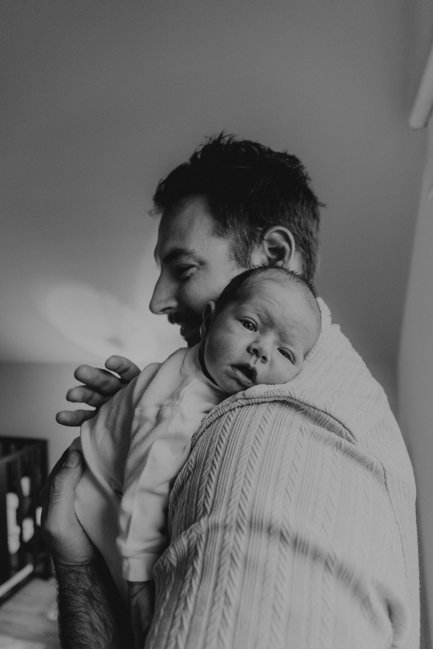 Kawartha Lakes Newborn Photography Session.
Black and white photo of dad holding newborn baby girl against his shoulder