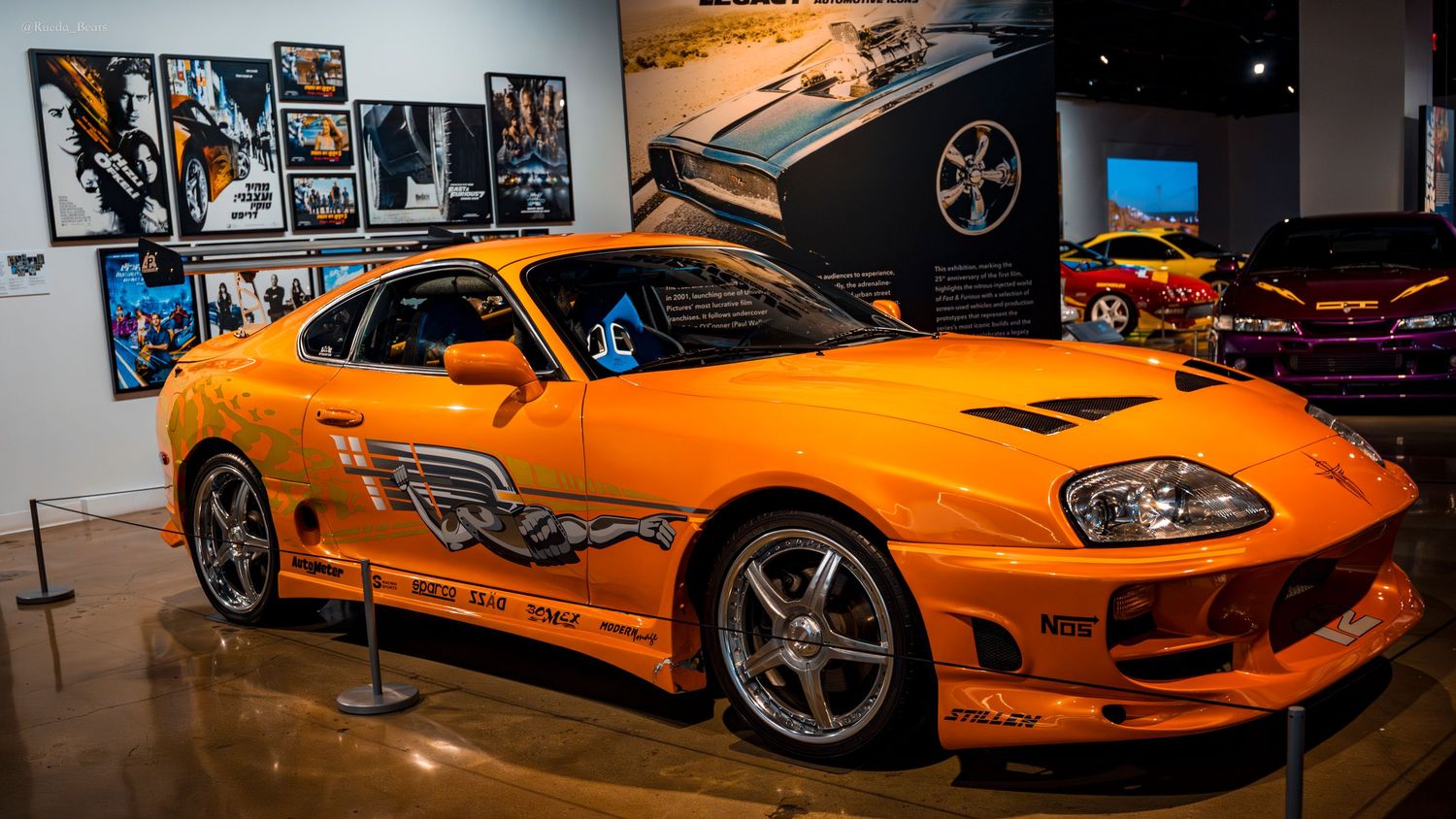Iconic orange Toyota Supra from Fast and Furious on display at a car museum exhibit.