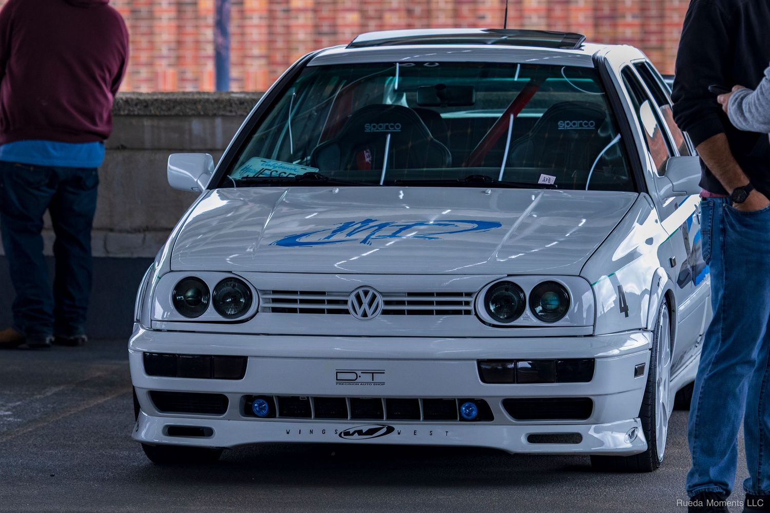 Modified white Volkswagen Golf Mk3 with wide body kit at an outdoor car show.