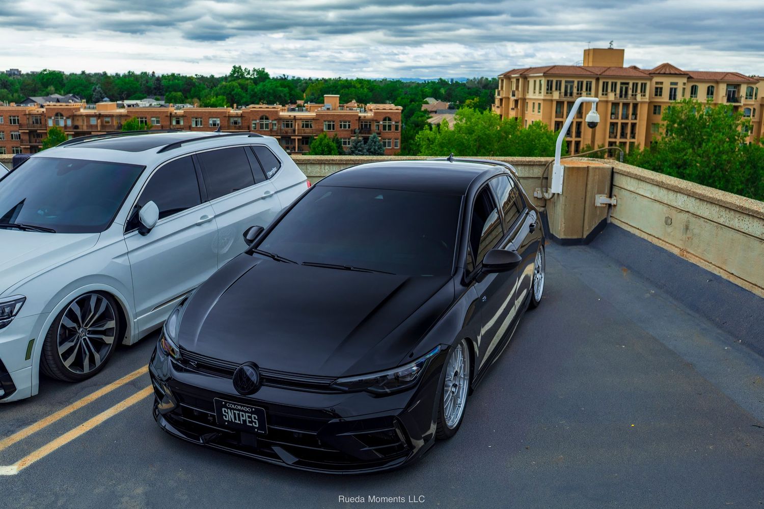 Blacked-out Volkswagen Golf R slammed on air suspension parked on rooftop lot.