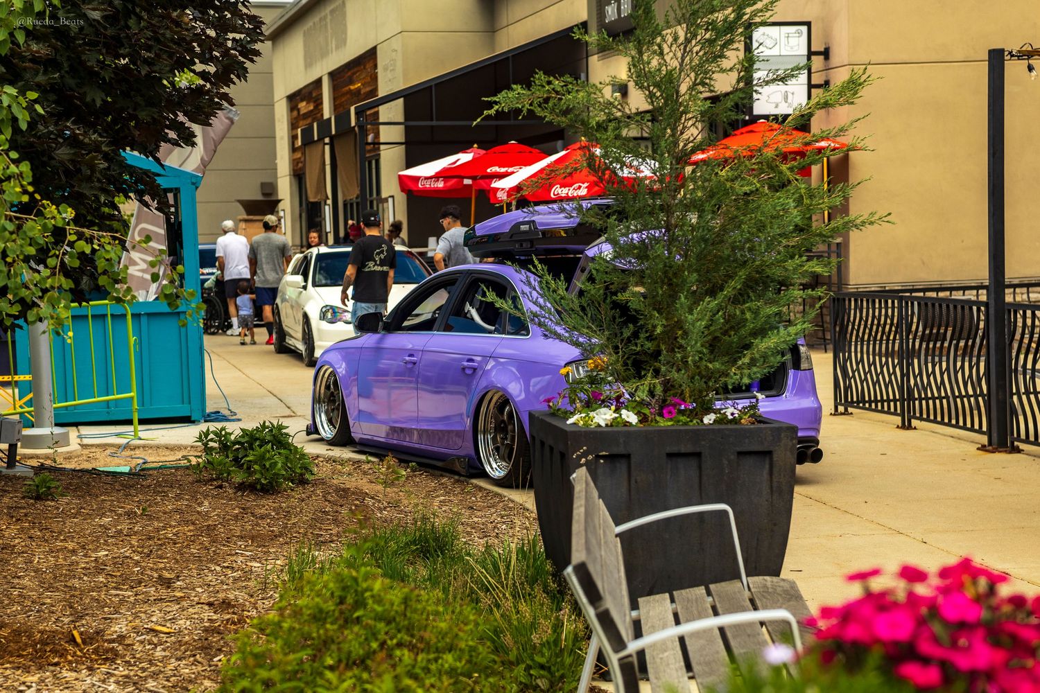Purple slammed custom car parked outside a shopping center during an outdoor car show event.