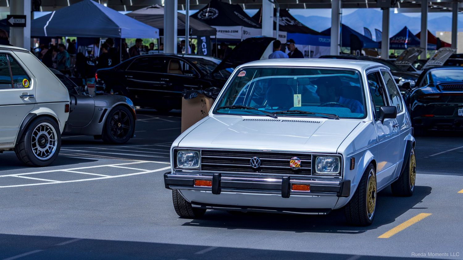 A classic white Volkswagen Golf MK2 with gold wheels parked at an outdoor car meet.