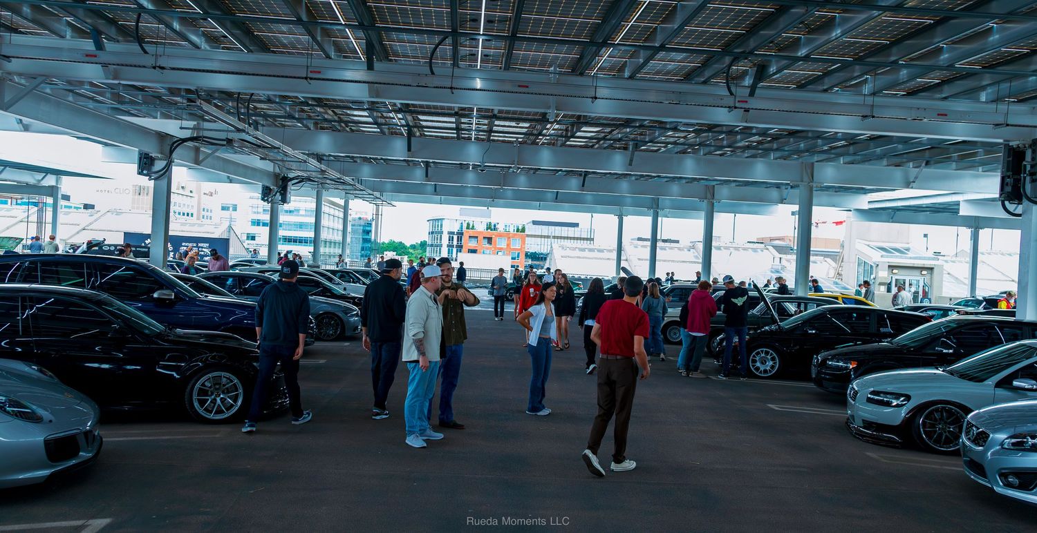Car enthusiasts browsing exotic and modified vehicles at an indoor car show.