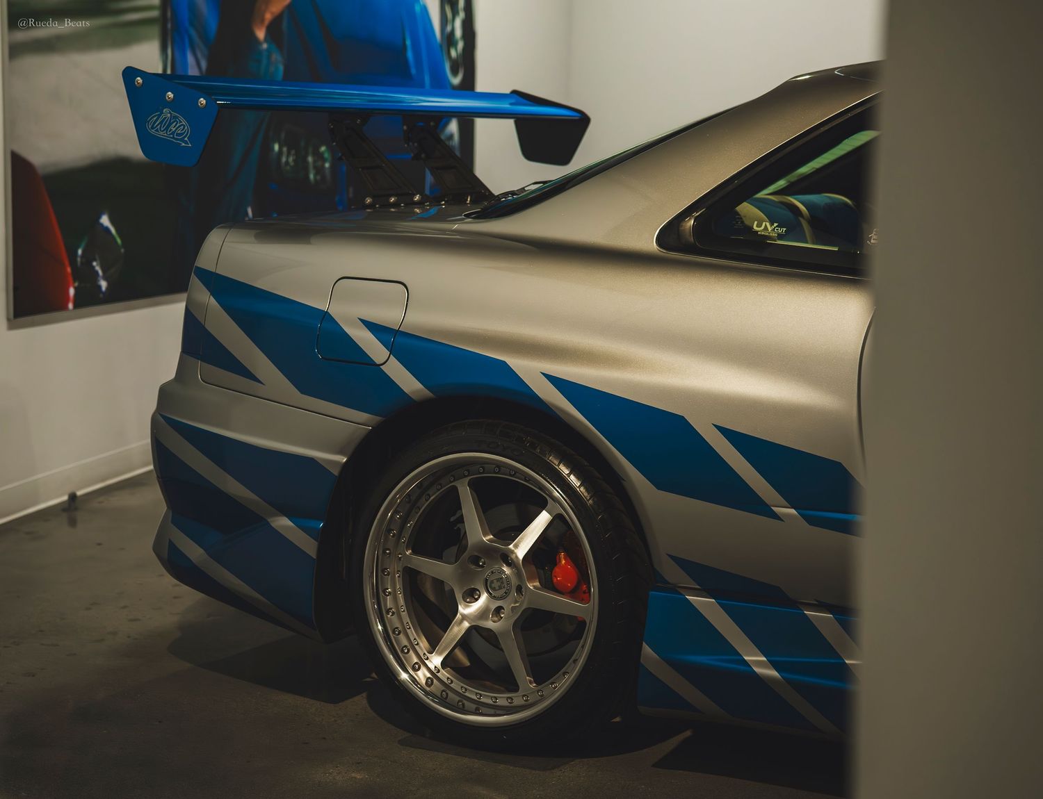 Silver and blue Nissan Skyline GT-R R34 detail shot showing custom paint and alloy wheels.