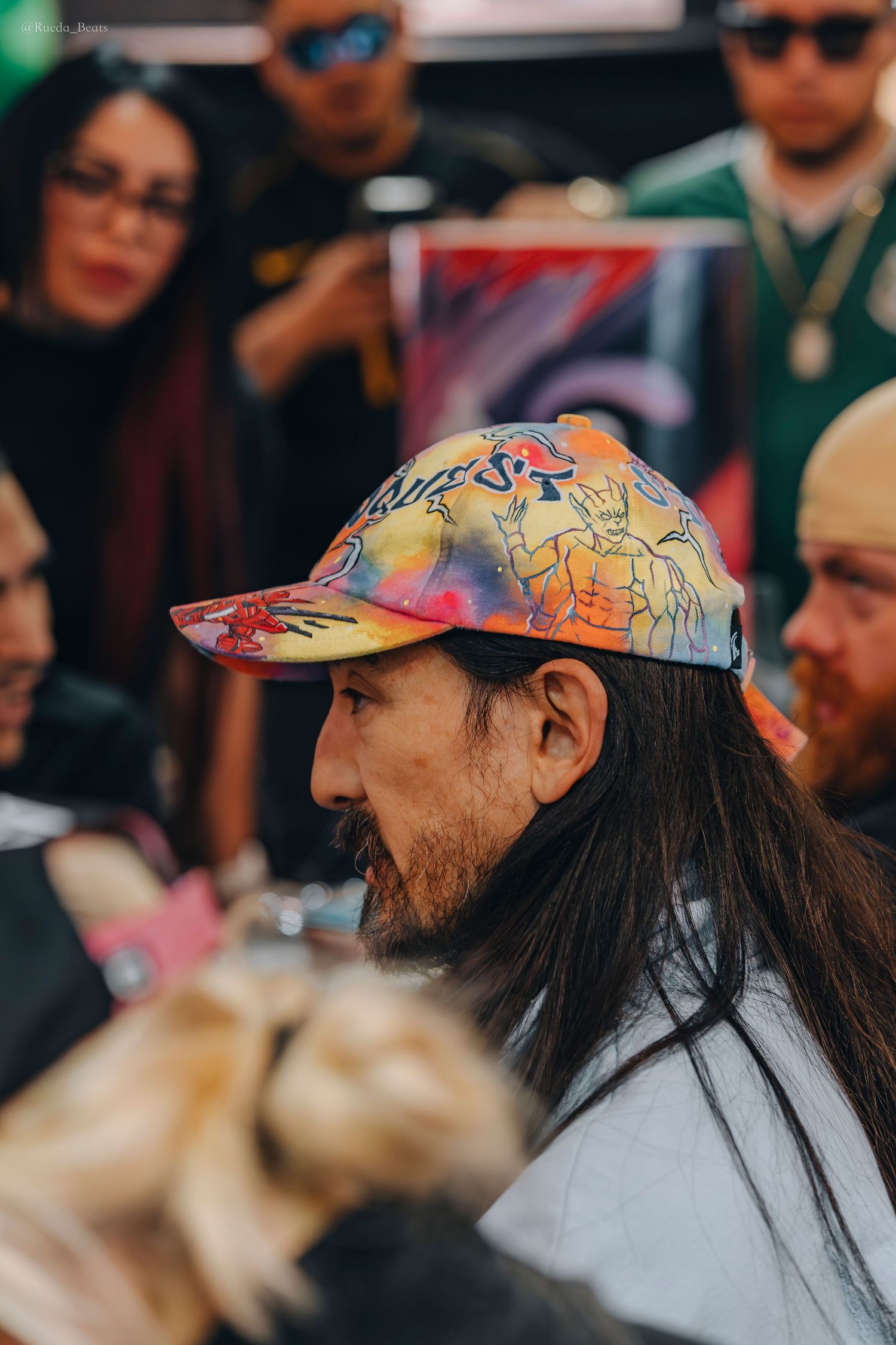 Side profile of man wearing vibrant hand-painted baseball cap at event.
