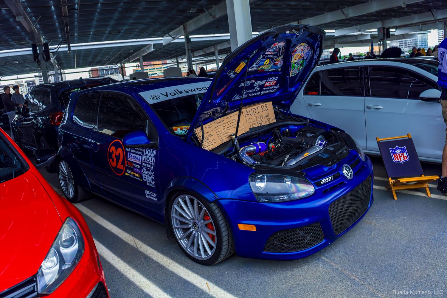Blue Volkswagen Golf R number 32 with open hood at an indoor car meet.