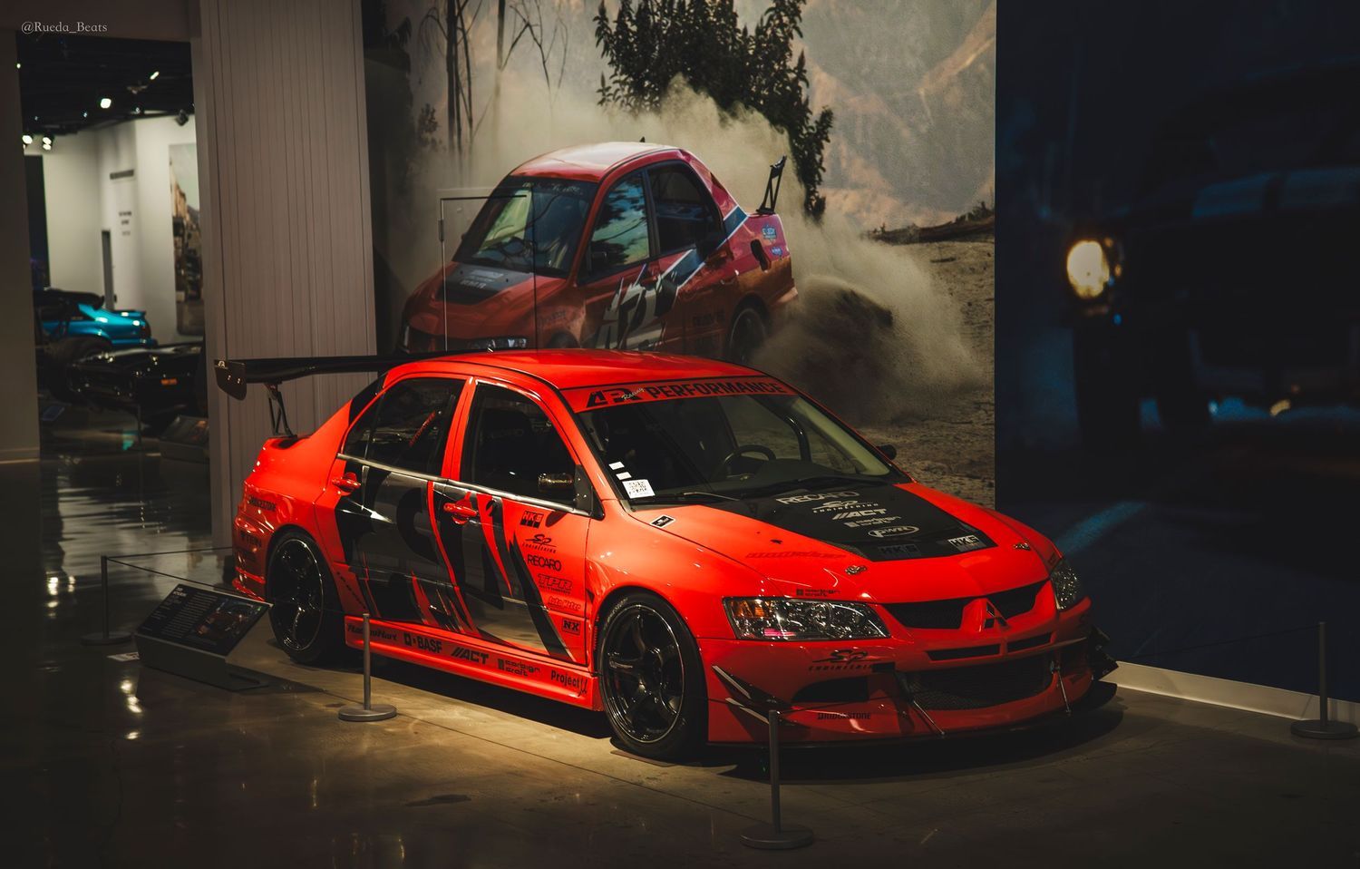 Red Mitsubishi Lancer Evolution with custom body kit on display at Fast and Furious car exhibition.