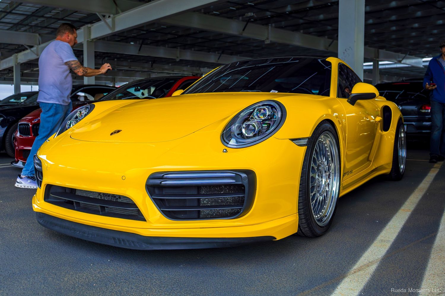 Bright yellow Porsche 911 Turbo S on display at an indoor car show event.