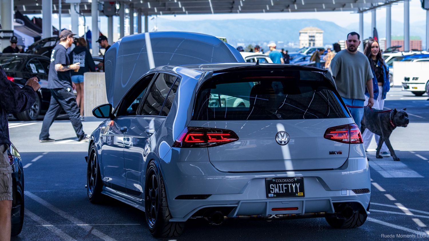 A modified silver Volkswagen Golf R with custom body kit displayed at an indoor car show.