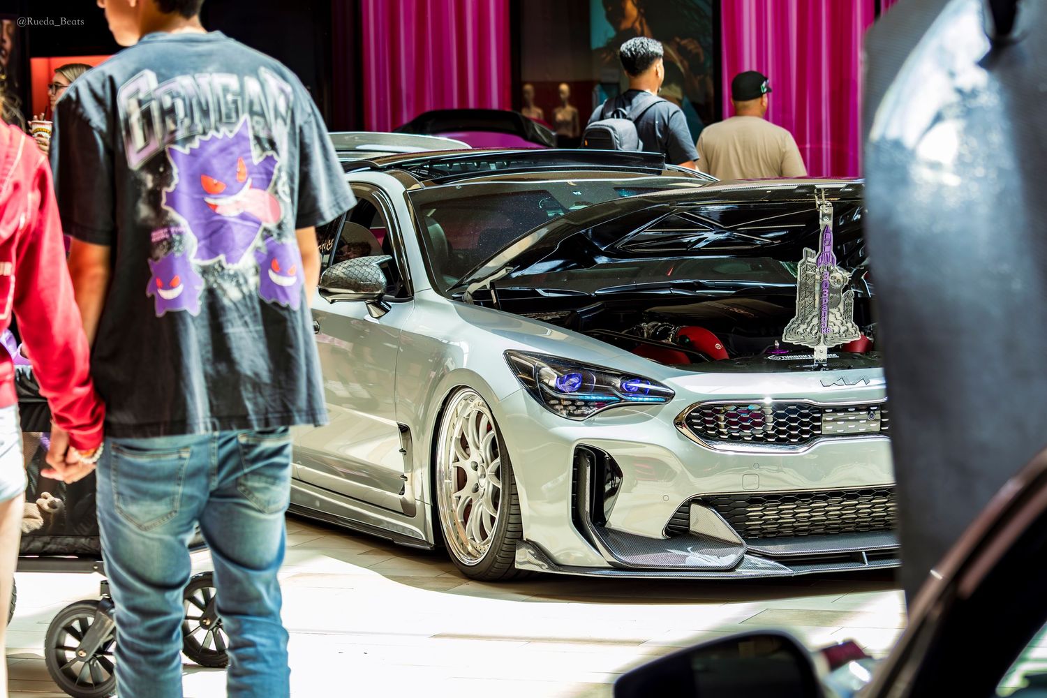 Modified Kia Stinger with aggressive body kit and lowered suspension at a custom car show.