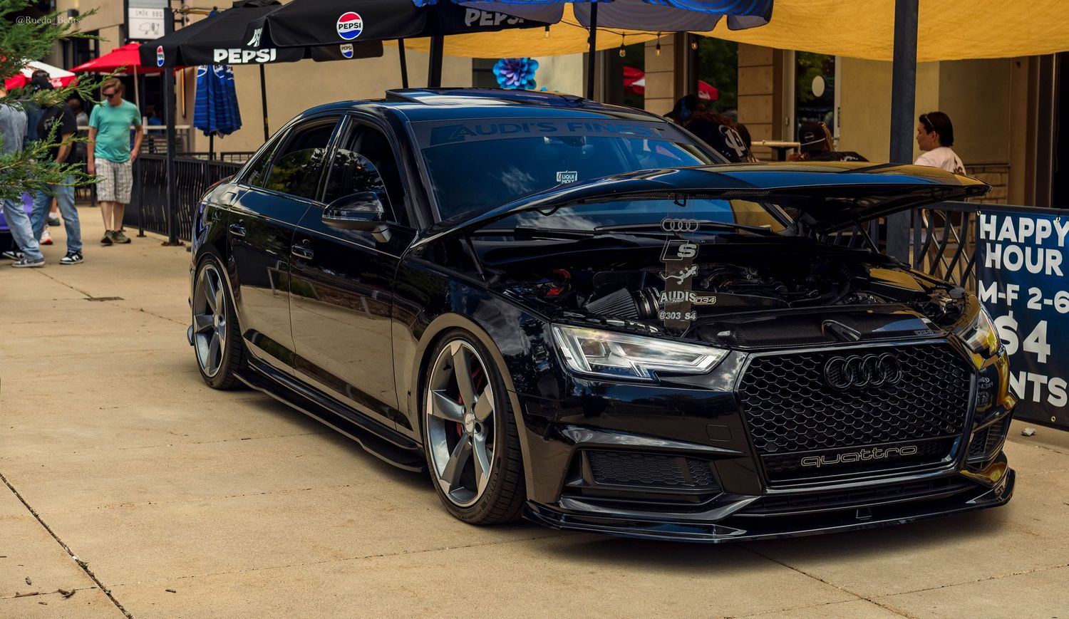 Blacked out slammed Audi S7 with aggressive front bumper at an outdoor car show.